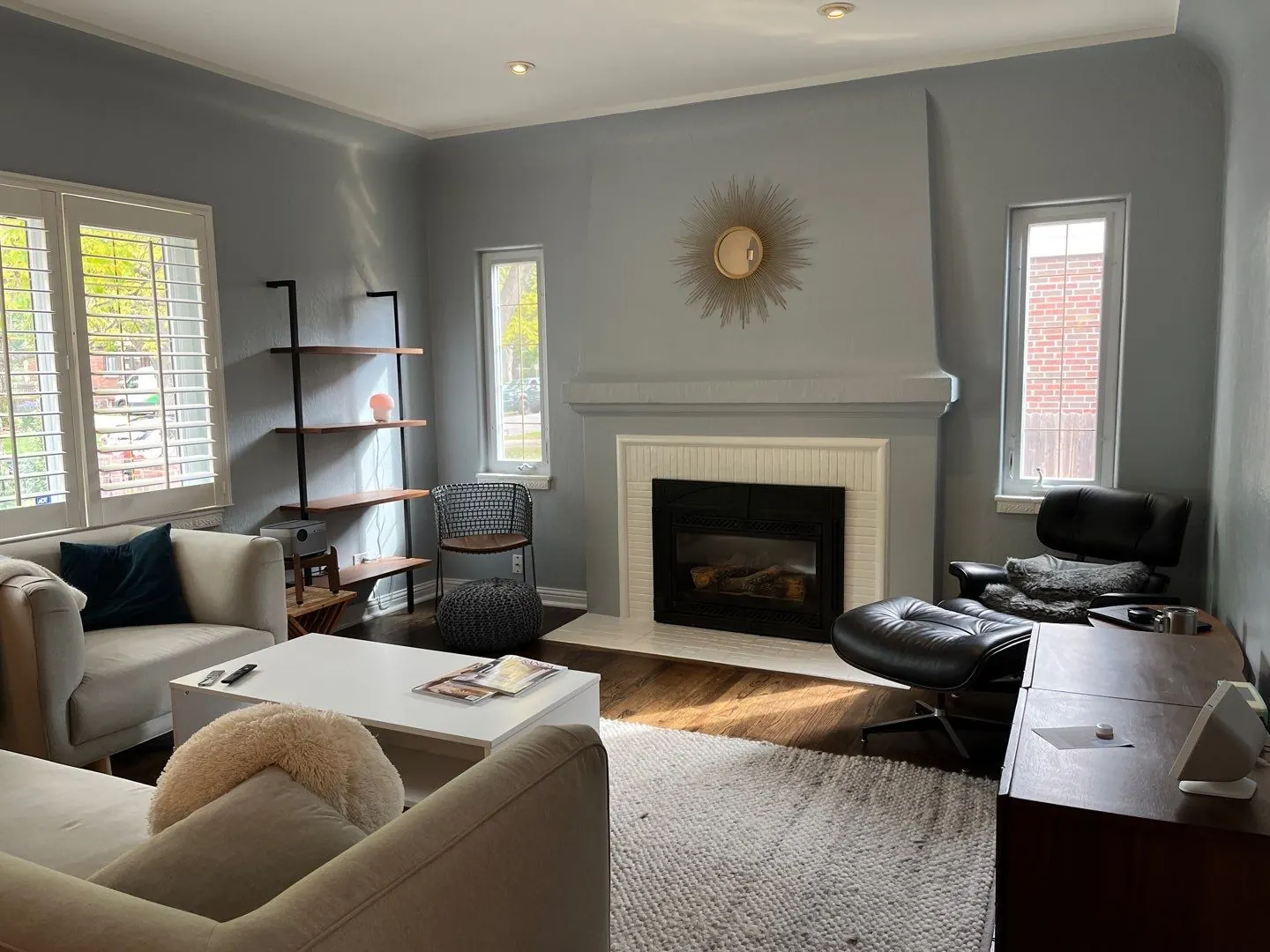 Repainted living room in soft blue-gray with white fireplace surround and built-in shelving